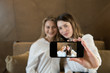 © Alvaro Hernandez/ADDICTIVE STOCK - Two stylish female friends with cups of fresh coffee smiling and posing for selfie while sitting at table in cozy restaurant