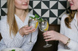 © Alvaro Hernandez/ADDICTIVE STOCK - Two pretty ladies smiling and clinking glasses of alcohol cocktails while having lunch in cozy restaurant together