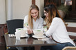 © Alvaro Hernandez/ADDICTIVE STOCK - Elegant women friends using phone while sitting at table of outdoor restaurant during lunch