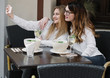 © Alvaro Hernandez/ADDICTIVE STOCK - Two stylish female friends smiling and posing for selfie while sitting at table in cozy restaurant