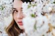 © Alvaro Hernandez/ADDICTIVE STOCK - Attractive lady smiling and looking at camera while standing near tree branches blooming with white flowers