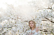 © Alvaro Hernandez/ADDICTIVE STOCK - Attractive lady looking at camera while standing near tree branches blooming with white flowers