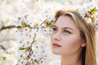 © Alvaro Hernandez/ADDICTIVE STOCK - Attractive lady smiling and looking at camera while standing near tree branches blooming with white flowers