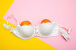 © elenarostunova - view of white bra with two oranges on pink and yellow, breasts concept