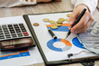 © Tania - Female hand with calculator and dollars on business graphs.