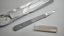 A Disposable Medical Grade Surgical Scalpel Laying On A White Table.
