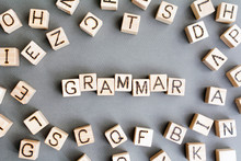 The Word Grammar Wooden Cubes With Burnt Letters, Study Of Grammar Of Different Languages,  Gray Background Top View, Scattered Cubes Around Random Letters