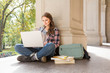 © ML Harris - Young woman female college university student with earbuds studying using laptop computer