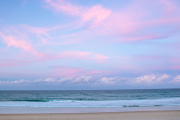 pretty pastel colour sky pink purple blue with fluffy cloud on beach with white sand australia gold 