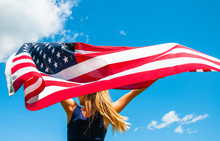 Woman Holding American Flag On Blue Sky Background. United States Celebrate 4th Of July