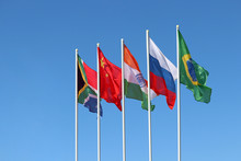 Waving Flags Of The BRICS Countries Against The Clear Blue Sky. The Summit Of Brazil, Russia, India, China And South Africa