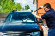 © Kiryakova Anna - Man washing his car under high pressure water outdoors.