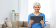 © Syda Productions - technology and old people concept - smiling senior woman using tablet computer over home living room background
