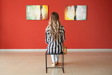 Woman Sitting On Chair In Modern Art Gallery