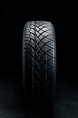 Brand new modern car tyre on a black background. Studio shot