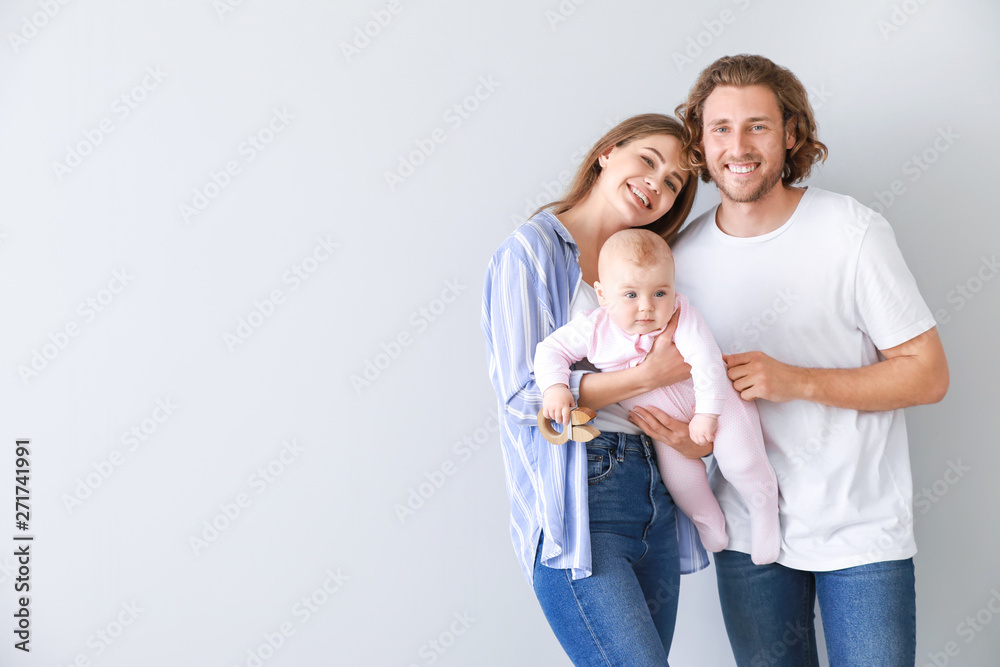 Happy parents with cute little baby on light background - obrazy, fototapety, plakaty 