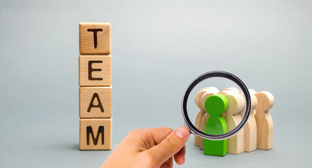 Wooden blocks with the word Team and a crowd of workers with a leader. The concept of a strong reliable business team. Teamwork. Team management. Choosing a new mentor. Wooden figures of people