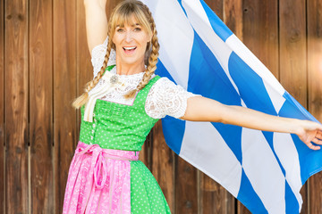 Wall Mural - Frau im Dirndl mit blonden Zöpfen freudig und mit Bayern Flagge 