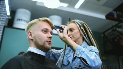 Canvas Print - the barber cuts a bearded man with scissors in the salon