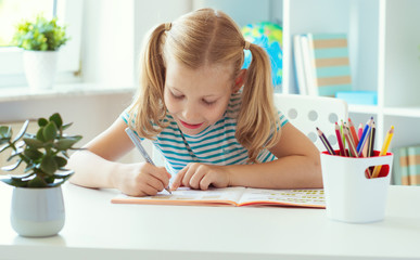 Portrait of schoolgirl at classroom writing at the table