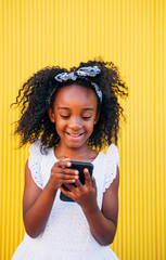 Happy kid girl using mobile in the street. Childhood outdoors