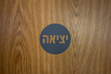 Exit sign in Hebrew on a woodgrain door