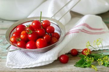 Ripe cherry tomatoes, celery leaves and dill, ingredients for canning on a wooden background.