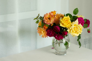 Wall Mural - Beautiful Bouquet of summer orange yellow and purple English roses in glass vase, jar near the big white window on table.