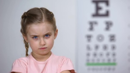 Wall Mural - Upset little girl rejecting glasses, child feels insecure in eyewear, discomfort