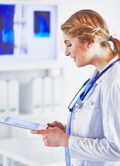 Young woman doctor is standing with board with clipboard smilin