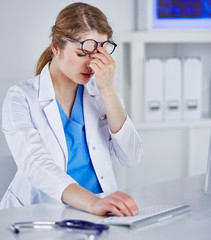 Wall Mural - Young female doctor tired after working with computer