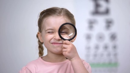 Wall Mural - Child testing vision with magnifier, diagnosis of cornea, eyesight illness