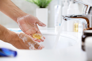  Soapy hands of adult with small piece of soap in the left hand