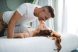 Romantic man on the bed above his woman looking at her and smiling