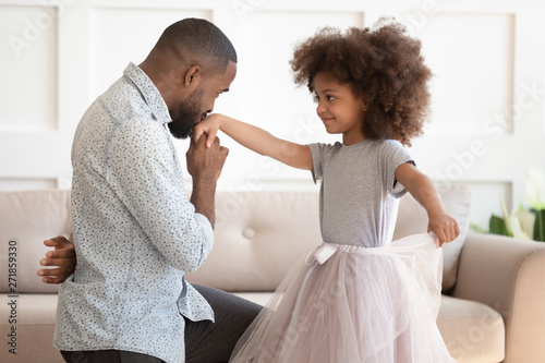 African dad standing on knee kissing hand of kid daughter Tableau sur Toile