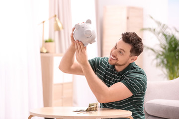 Poster - Man with piggy bank and money at home