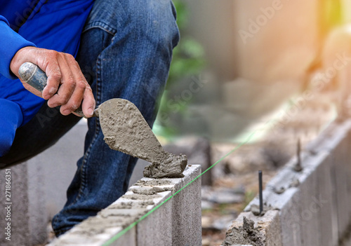 Cuadros en Lienzo Worker is cementing bricks with cement for brick in construction site