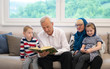© .shock - modern muslim grandparents with grandchildren reading Quran