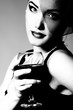 © Khorzhevska - Pretty lady inhat with veil holding glass of wine, retro glamour beauty portrait. Beautiful woman with perfect makeup looking at camera, high fashion look, black and white