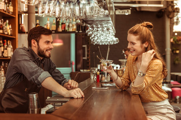 Wall Mural - Red-haired woman talking to bartender while holding a cocktail