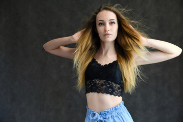 Photograph of a portrait of a beautiful girl woman with long dark flowing hair, happy life on a dark gray background. She is standing directly in front of the camera in various poses and smiling.