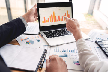 two young businessmen partner explaining information and pointing at report data discussing strategy agreement or contract at office, Teamwork, cooperation.