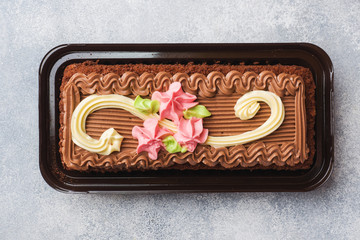 Wall Mural - Chocolate rectangular cake decorated with cream roses. Sweet food is a confectionery business. Top view