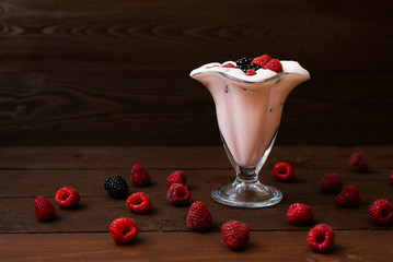 Wall Mural - A glass of milkshake with fresh organic raspberry on a background of brown wooden boards with a copy of the space After