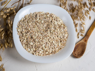 Oat flakes and ears of oats. Oatmeal in a plate on the table. Healthy breakfast