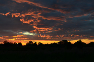 Silhouette of a houses with a gradient blue orange sky during a beautiful sunset in rural village of Russia, Vologda.