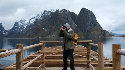 Fototapete - Professional photographer male taking photo of valley with DSLR wearing backpack photographing scenic landscape nature travel adventure Norway