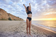 © taraspolatayko - Happy smile brunette Woman wearing black swimsuit at ocean background , hands raised up to the sky