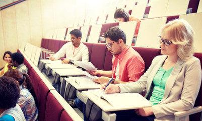 Poster - education, high school, university, learning and people concept - group of international students writing test at lecture hall