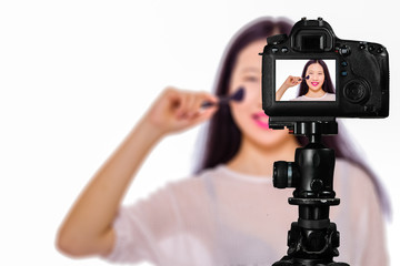 Focus on live view on camera on tripod, teenage girl   with blurred scene in background. Teenage vlogger livestreaming show concept